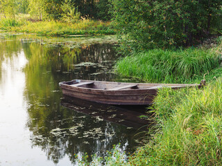 A boat on the river bank. A grassy bank. Rural area