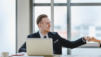Fototapeta premium Executive caucasian man smile and bump fist with colleague woman as happy for professional team agreement on amazing business solution and success to win corporate deal at conference room