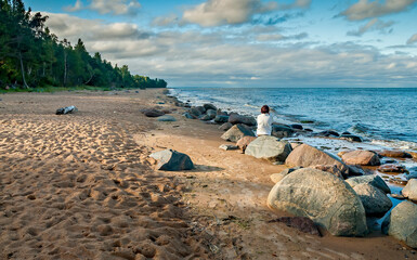 
Stony beach of the Baltic Sea at autumnal weather and single woman looking at the distance
