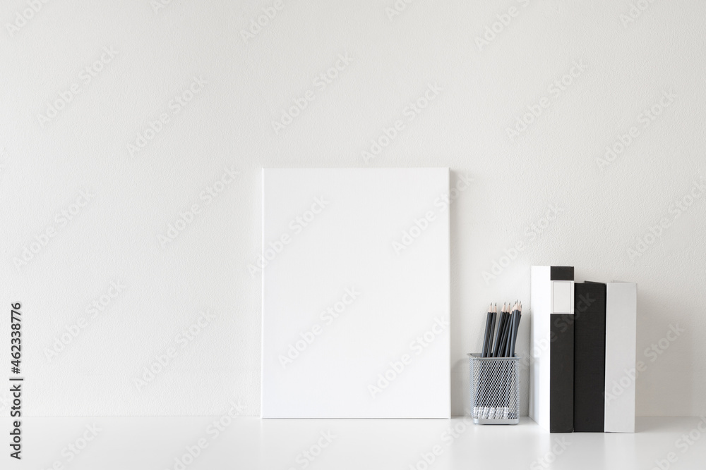 Wall mural office desk workspace with blank canvas frame and stationery supplies on white background. front vie