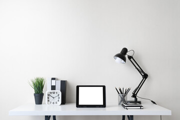Office desk workspace with blank screen digital tablet computer and supplies on white background. Front view with copy space.