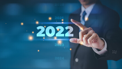 Businessman in a suit chooses his hand 2022 on a black background. new year start ideas It is a...