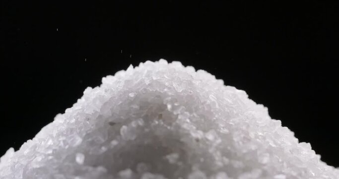 Close up shot of salt granules falling. Spice particles being dropped. Bath cosmetic salt forming a pile 4k footage