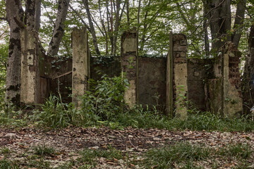 A destroyed brick outdoor toilet in the middle of a park near an abandoned restaurant.