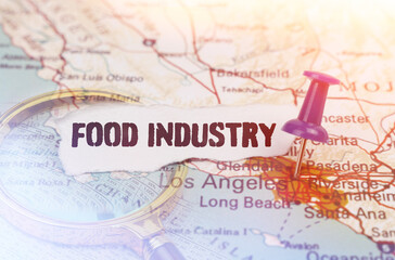 Fototapeta na wymiar On a map of Los Angeles, next to a magnifying glass and paper with the inscription - food industry