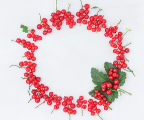 creative frame of red currant berries laid out in a circle on a white background, space for text