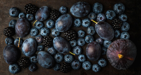 Dark background with ripe dark berries and figs. Shot from above. Background and textures. Selective focus.