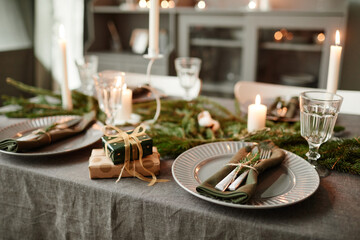 Background image of cozy dining room decorated for Christmas with candles lit and fresh fir branches, copy space