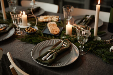 Close up background image of black table setting decorated for Christmas with candles lit, copy space