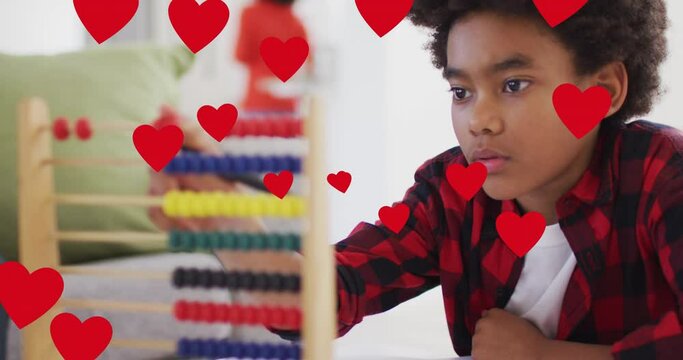 Animation of social media heart icons over smiling biracial boy using abacus