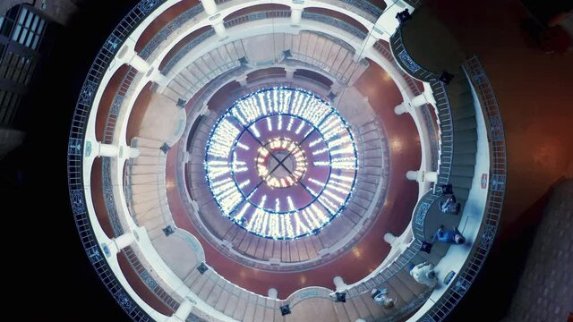 Hypnotic top down aerial 4K drone rotating above spiral staircase with tourists going down. Cinematic illuminated circling spiral stairs in European architecture style, night scene impressive design - Powered by Adobe