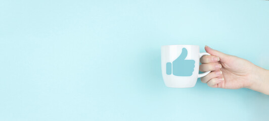 Tumb up concept. Girl hand hold morning coffee cup with hand tumb up. Copy space. Blue background....