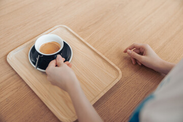 Female hand holding black cup of coffee