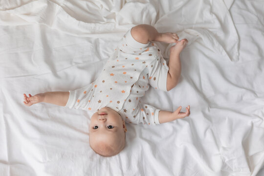 cute cheerful newborn baby is lying on his back on a white sheet. top view. lifestyle. High quality photo