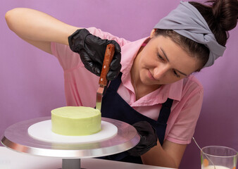 The woman aligns the cream on the side of the bento cake with a scraper. The assembly process....