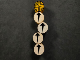 Wooden block cylinder are arranged vertically with black arrows or the path to success.