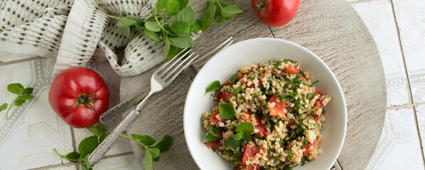 a bowl of Lebanese tabbouleh salad with tomatoes, parsley, tuna and bulgur on a light table