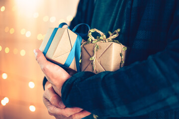 Hands holding gift box, present on the table and light of bokeh background. Valentine's Day,...