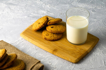 oatmeal cookies and a glass of milk on a wooden cutting board on the table