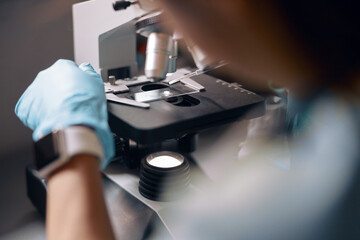 Lab assistant in gloves puts material sample onto slide at microscope working in laboratory