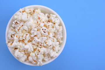 Popcorn in bowl on a blue background. Close up. Top view