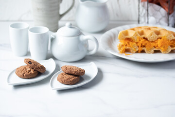 Cookies in a white plate, teapot, afternoon snack.