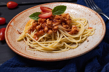 Fried spaghetti with chicken sauce in black background plate