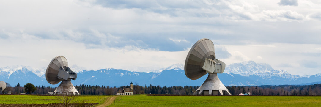 Bavarian landscape with two satellite dishes (Raisting radome). In the distance a church and Zugspitze mountain.