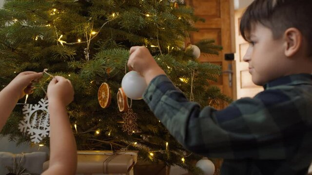 Sibling decorating Christmas tree together. Shot with RED helium camera in 8K 