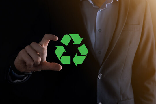 Businessman in suit over dark background holds an recycling icon, sign in his hands. Ecology, environment and conservation concept. Neon red blue light