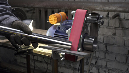 Working process on lathe with grinding belt in workshop - obrazy, fototapety, plakaty