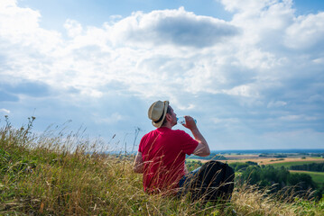 Traveler drinks water in the mountains.Hiker with backpack relaxing on top of the mountain in summer sunny day.