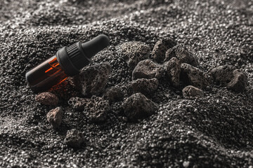 Essential oil for aromatherapy and mineral diffuser with volcanic stones in iron metal box on black sand  background. Aromatherapy, spa, beauty treatment and wellness concept.