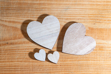 Four wooden hearts of different sizes flat lay on a brown wooden background. Love, family and Valentine's Day concept.