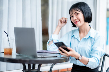 Smiling with dental braces asian freelance people Businesswoman writing message on smartphone casual working with laptop computer with a coffee cup mug at the cafe,Business Lifestyle