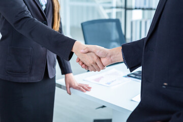 businesswoman and businessman shaking hands at In the office room background after the contract is signed or handshake greeting deal,business expressed confidence embolden and successful concept