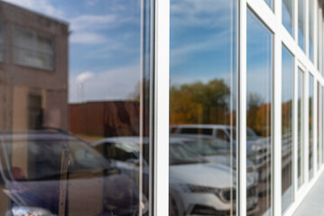 Office building or apartment house with cars parking reflection on a cloudy summer day.Business background.Selective focus.