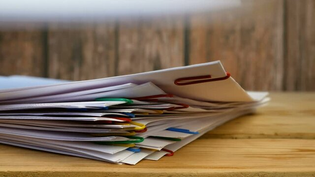 stack of many documents with binder clips wooden table. Stop motion animation
