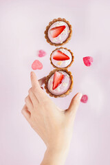 dessert with strawberries on a pink background in female hands. healthy vegan dessert. St. Valentine's Day. marmalade in the form of hearts