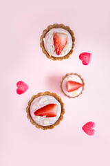 Healthy vegan cakes with strawberries and marmalade in the shape of hearts on a pink background, top view.