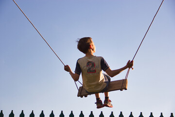 child on a rope swing against the background of the sky