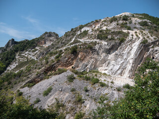 Fototapeta na wymiar View of a Mountainside in Carrara in Summer Time with Rocks Covered by Vegetation and Trees