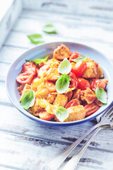 Farfalle pasta with chicken breast, cherry tomatoes and fresh basil. Bright wooden background.