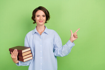 Photo of young woman happy positive smile hold book point finger empty space ad promo isolated over green color background