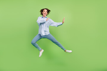 Fototapeta na wymiar Full size photo of cheerful young nice happy woman jump up fighter amazed excited isolated on green color background
