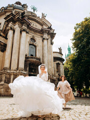 Cute bride with girlfriends running near the church in the Baroque style. Walks through the old European city.