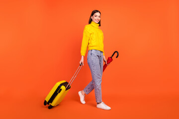 Full length profile side photo of young woman happy smile go walk airport luggage travel isolated over orange color background