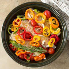 round baking sheet with cod fillet with vegetables