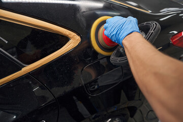 Cropped view of service worker polishing car during auto detailing
