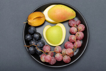 fresh fruits grape, apple, pear, plum in the plate